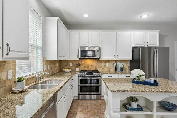 a kitchen with stainless steel appliances granite countertop a sink stove and refrigerator