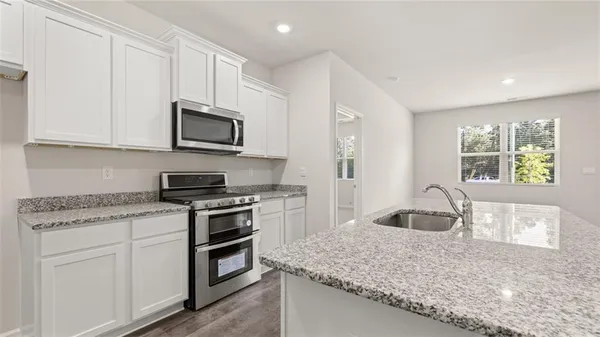 a kitchen with granite countertop a stove sink and microwave