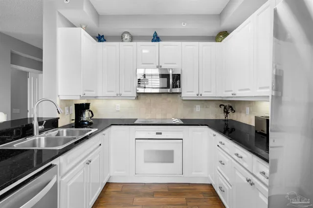 a kitchen with granite countertop white cabinets white stainless steel appliances and a sink