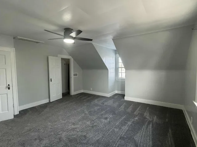 an empty room with an entryway and chandelier fan