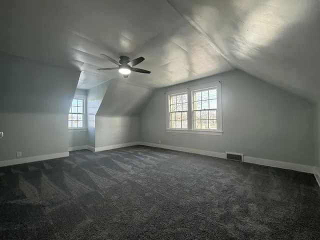 an empty room with windows and ceiling fan
