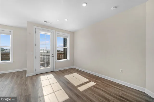 a living room with stainless steel appliances granite countertop furniture wooden floor and a large window