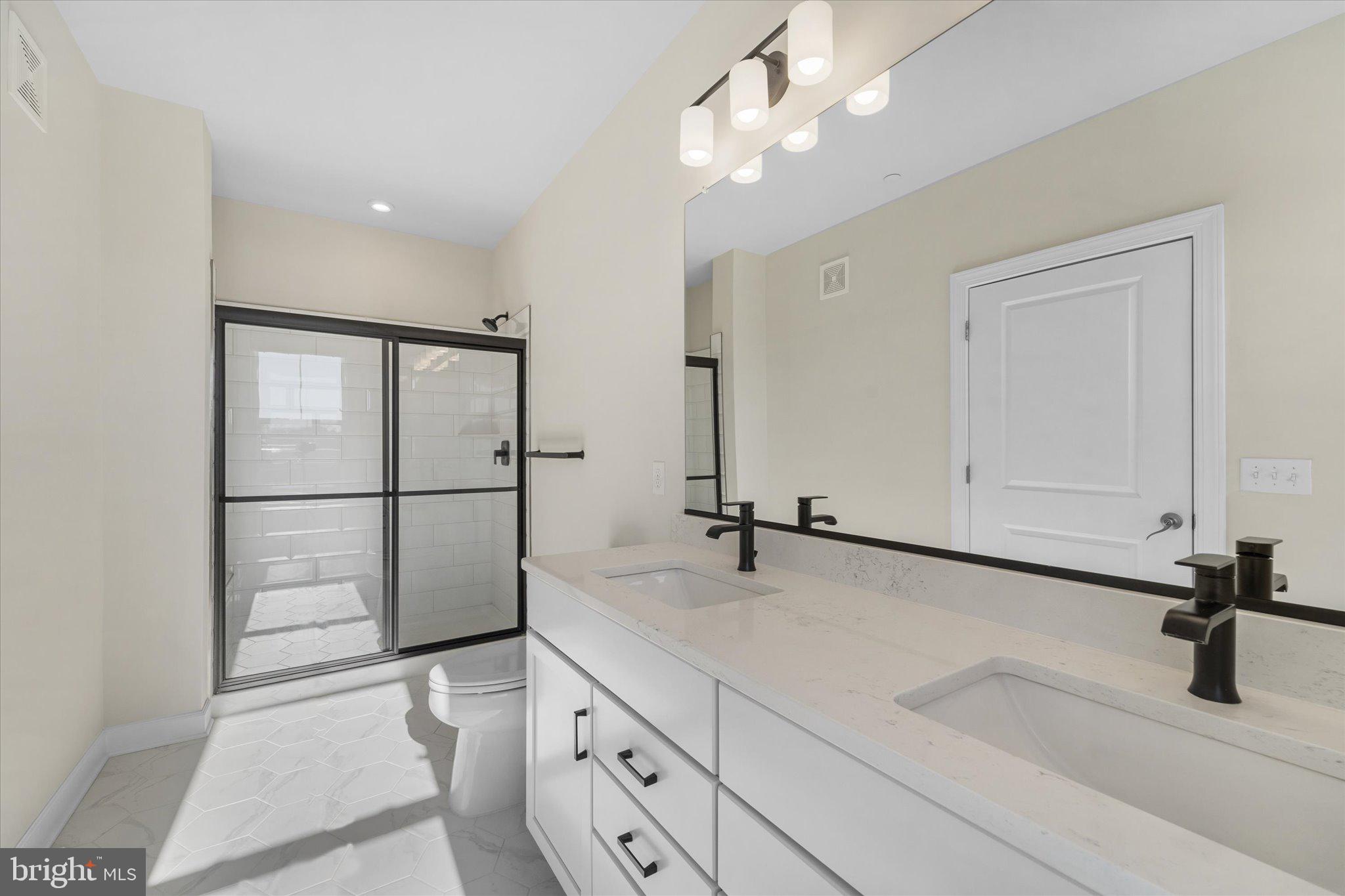 3927 Fair Ridge Drive, Unit 409 Fairfax, VA 22033 - Photo 18 of 37 a bathroom with a sink a light fixture and a glass door shower