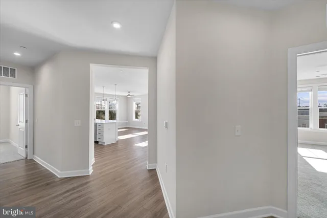 a view of a hallway with wooden floor and a bathroom