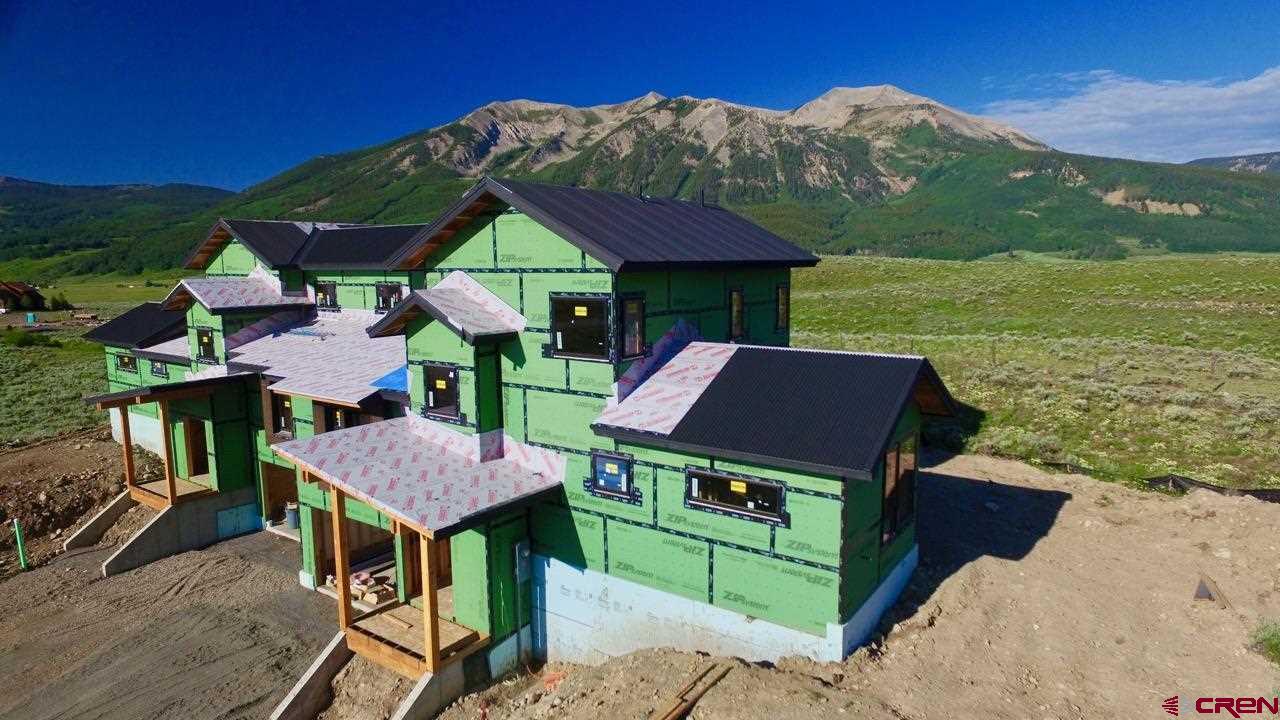 138 Elk Valley Road, Unit B Crested Butte, CO 81224 - Photo 1 of 19 a view of a table and chairs under an umbrella in front of house