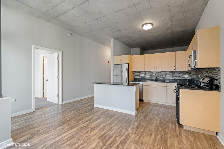 235 West Van Buren Street, Unit 1502 Chicago, IL 60607 - Photo 12 of 30 a kitchen with granite countertop white cabinets and white appliances