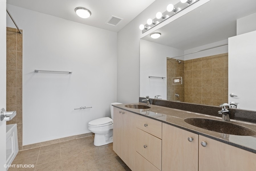 235 West Van Buren Street, Unit 1502 Chicago, IL 60607 - Photo 19 of 30 a bathroom with a granite countertop sink a toilet and a mirror