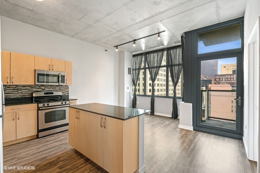 235 West Van Buren Street, Unit 1502 Chicago, IL 60607 - Photo 9 of 30 a kitchen with stainless steel appliances granite countertop a refrigerator and a stove top oven