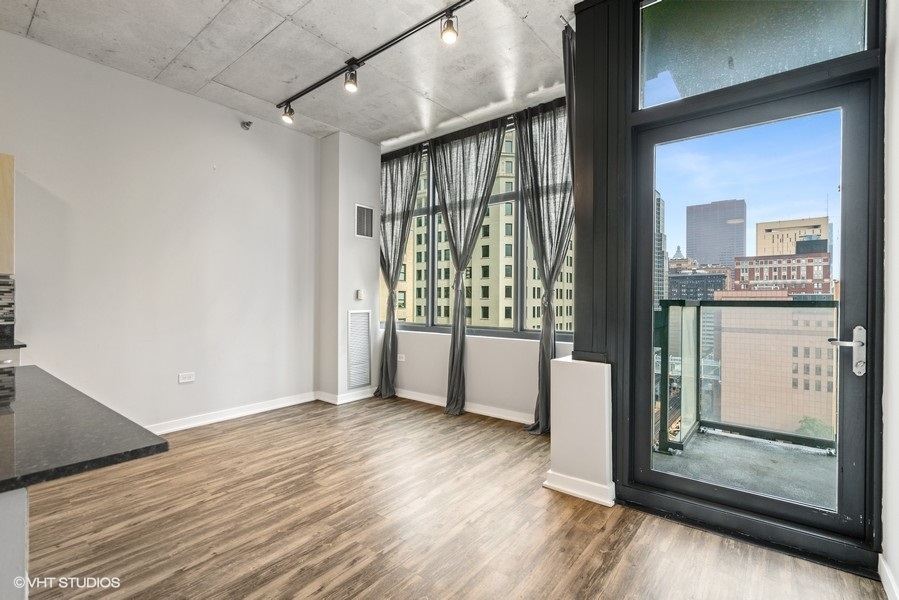 235 West Van Buren Street, Unit 1502 Chicago, IL 60607 - Photo 10 of 30 a view of an empty room with wooden floor and a window