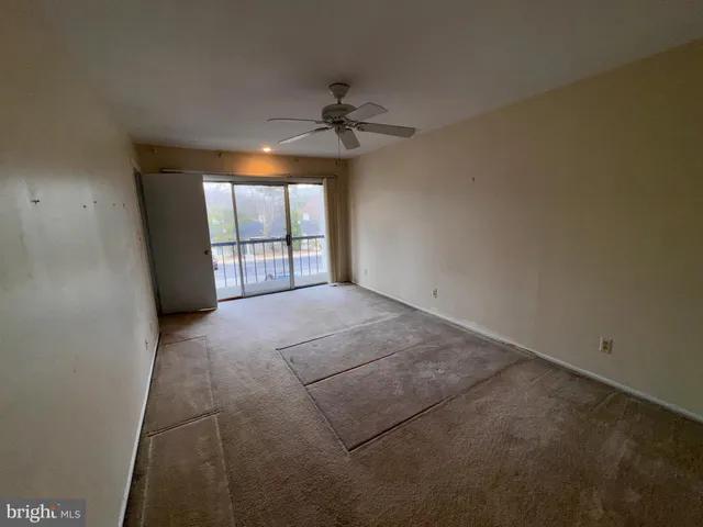 an empty room with a chandelier fan and windows