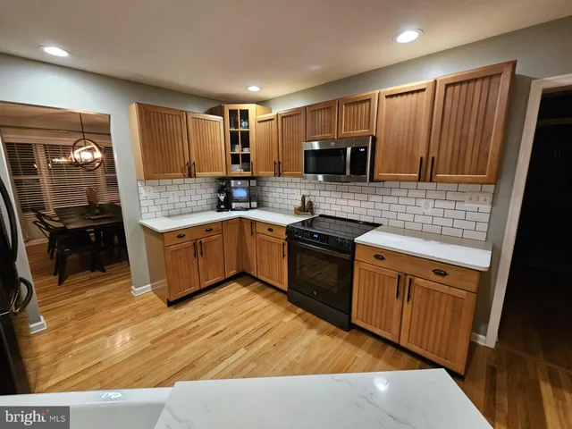 a kitchen with stainless steel appliances kitchen island granite countertop a sink counter space cabinets and a couch