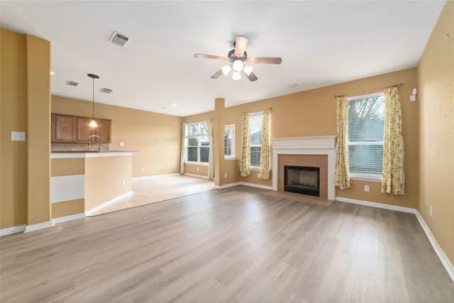 a view of a livingroom with wooden floor a ceiling fan and windows