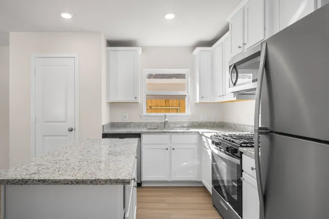 a kitchen with granite countertop a sink stove and refrigerator