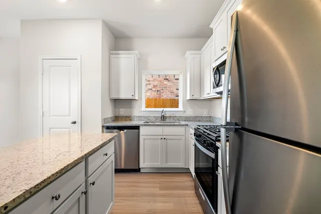 a kitchen with stainless steel appliances granite countertop a stove a sink and a refrigerator