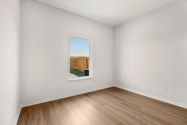 an empty room with wooden floor and a window