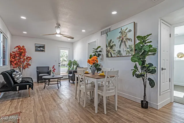 a living room with furniture flowers and wooden floor