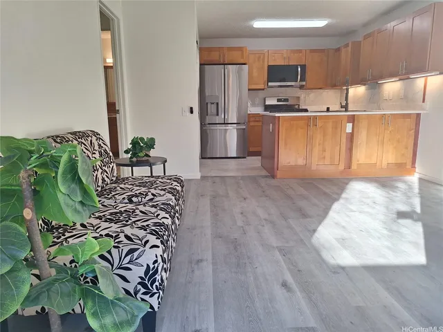 a kitchen with stainless steel appliances kitchen island granite countertop a refrigerator a stove and a wooden floors