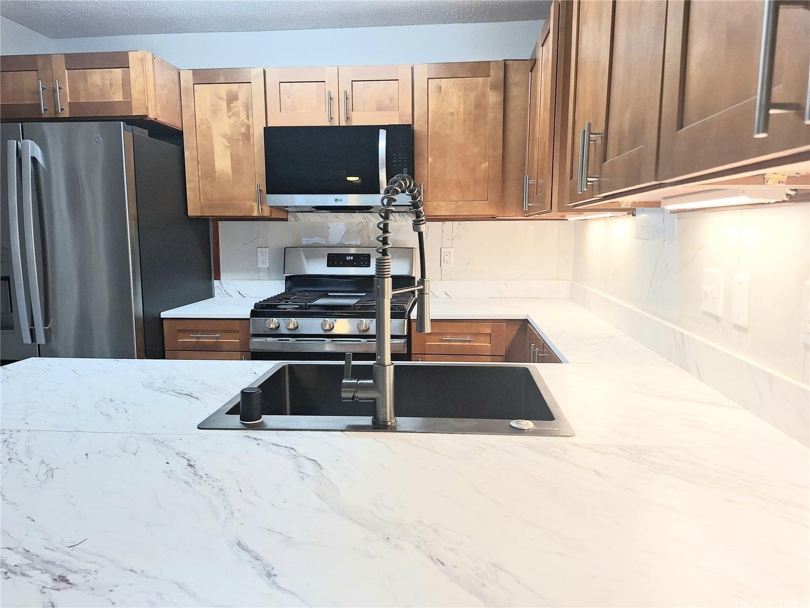Undisclosed Address Ewa Beach, HI 96706 - Photo 4 of 11 a kitchen with granite countertop a refrigerator and a stove top oven