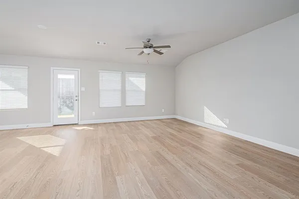an empty room with wooden floor ceiling fan and windows