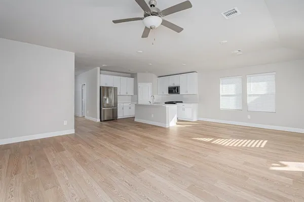 a view of empty room with wooden floor and ceiling fan