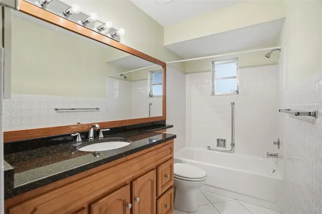 a bathroom with a granite countertop sink a toilet a mirror and shower