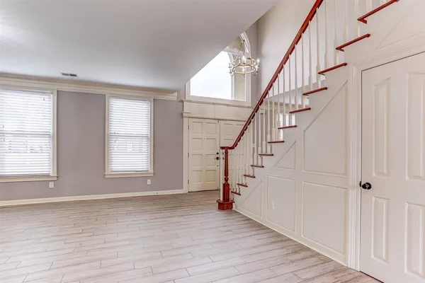 a view of an empty room with wooden floor fireplace and a window