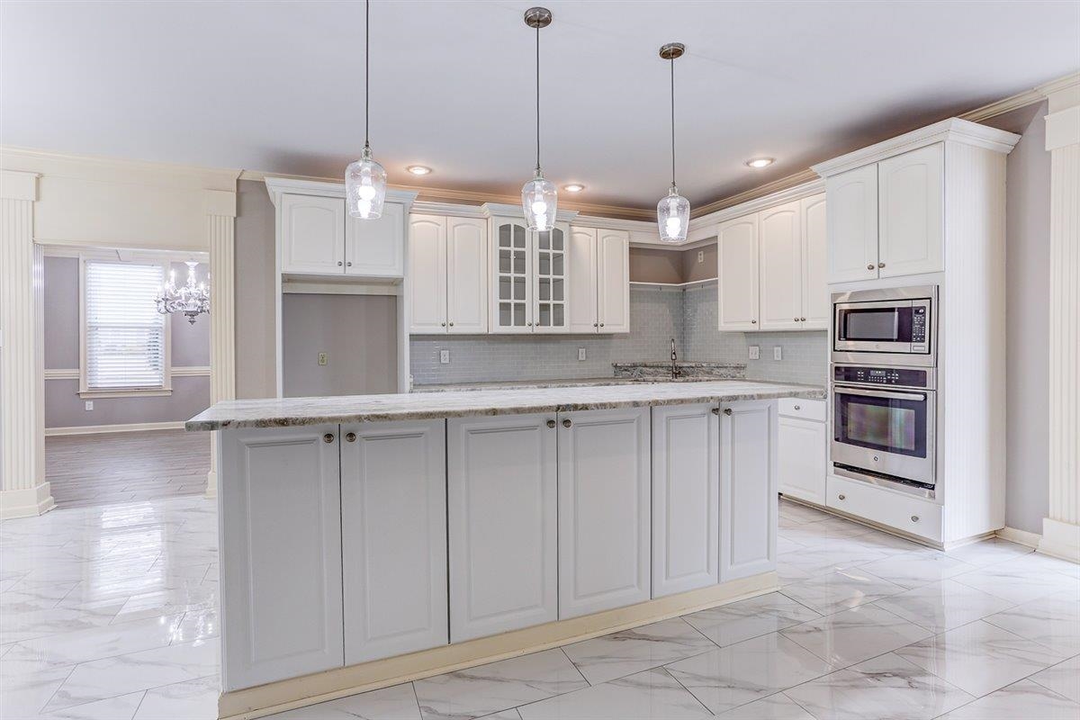 608 Roxburgh Drive Collierville, TN 38017 - Photo 10 of 40 Kitchen featuring light stone counters, stainless steel appliances, ornamental molding, decorative light fixtures, and light marble finish floors