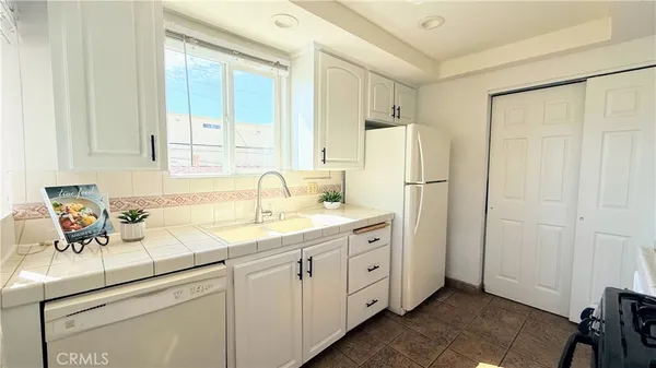 a kitchen with white cabinets and white refrigerator