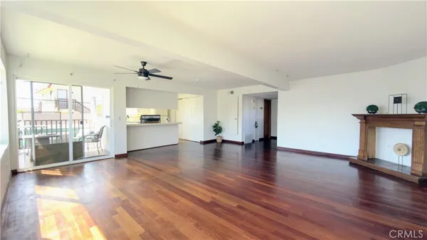 a view of a livingroom with wooden floor and a kitchen