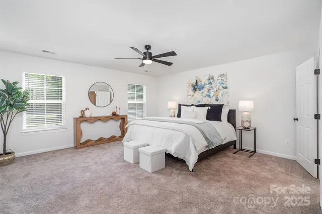 a spacious bedroom with a bed a mirror and a large window