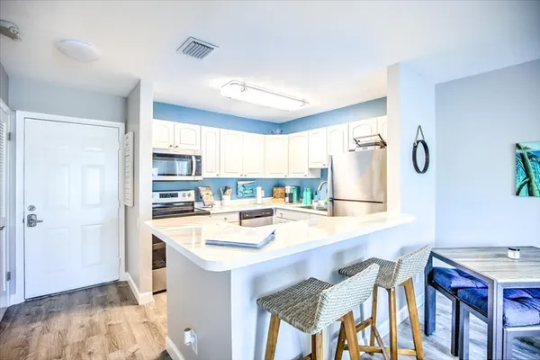 a room with stainless steel appliances kitchen island granite countertop a table chairs and a refrigerator