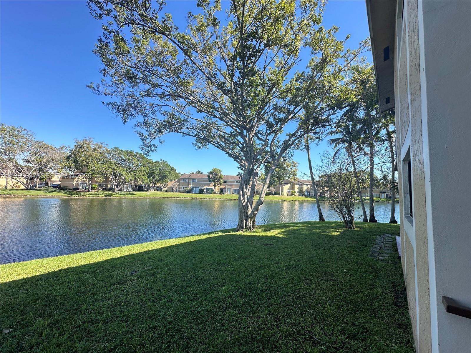 301 Palm Way, Unit 206 Pembroke Pines, FL 33025 - Photo 20 of 23 a view of a lake with a yard and large trees