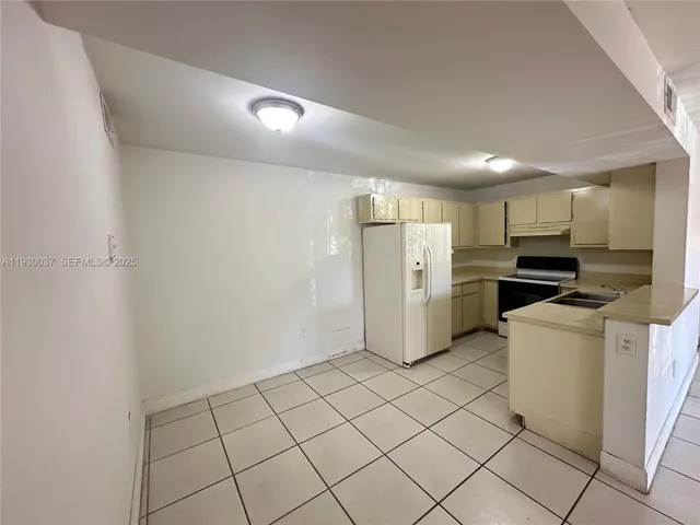 a view of a kitchen with refrigerator and white cabinets