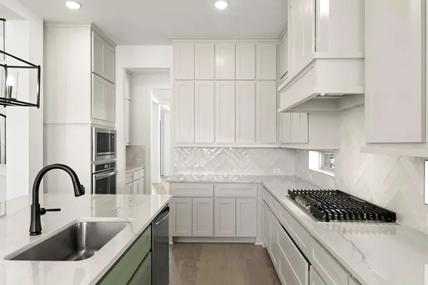a kitchen with white cabinets a sink and appliances