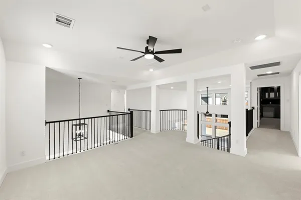 an empty room with chandelier fan and windows