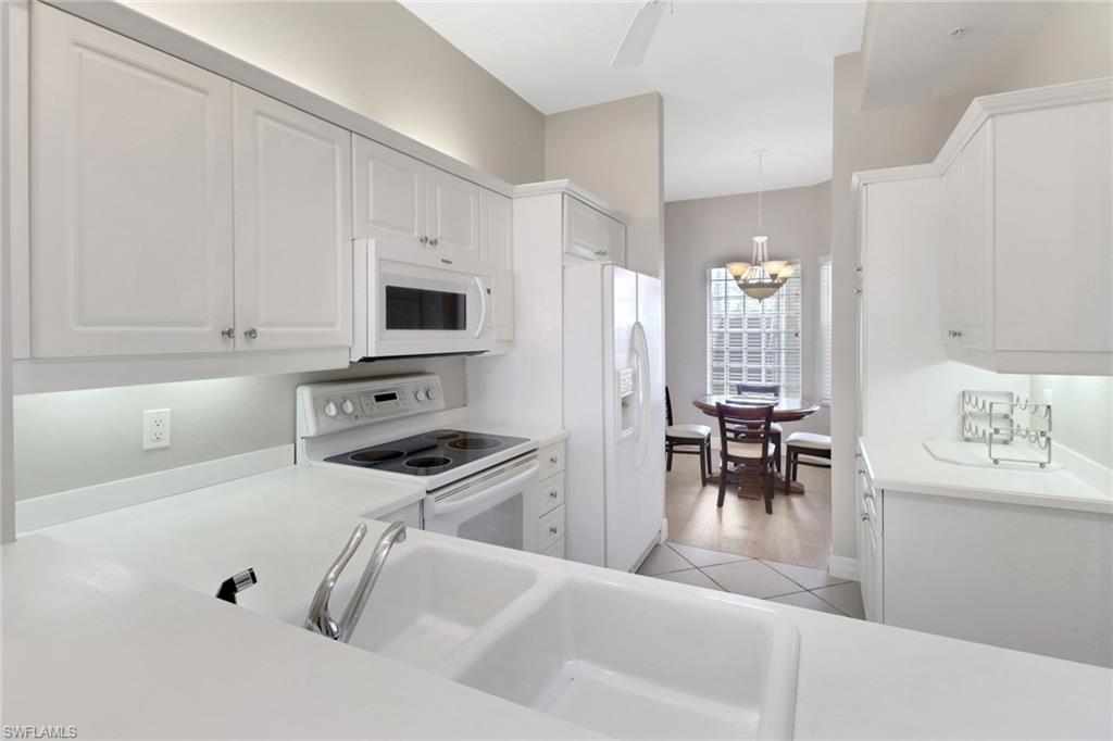 401 Bayfront Place, Unit 3502 Naples, FL 34102 - Photo 5 of 22 Kitchen featuring white appliances, white cabinets, light countertops, and decorative light fixtures