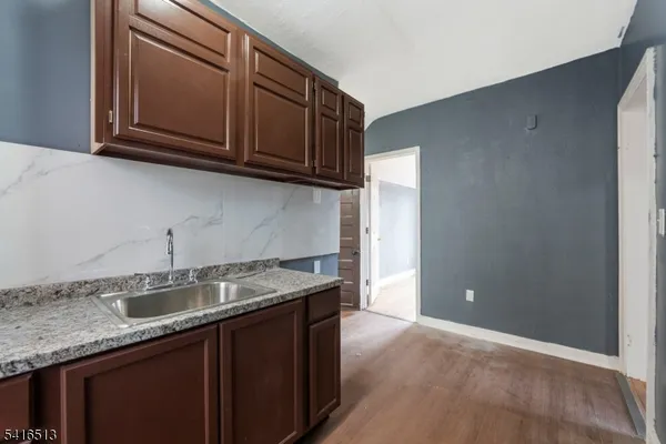 a kitchen with granite countertop a sink a stove and cabinets