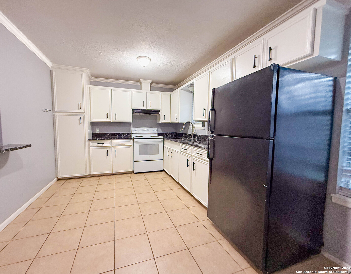1403 West Hefferman Street Beeville, TX 78102 - Photo 7 of 15 a kitchen with white cabinets a refrigerator and a stove top oven