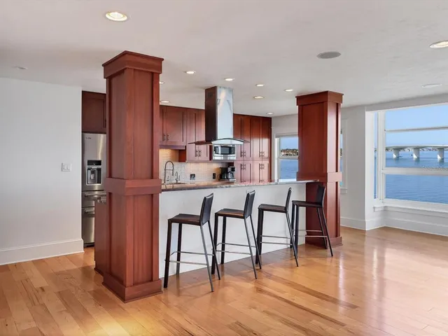 a kitchen with stainless steel appliances a dining table chairs refrigerator and cabinets