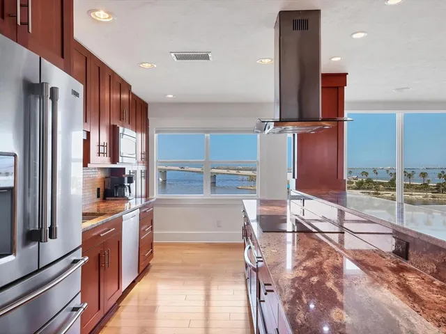 a kitchen with stainless steel appliances kitchen island granite countertop a refrigerator and a stove