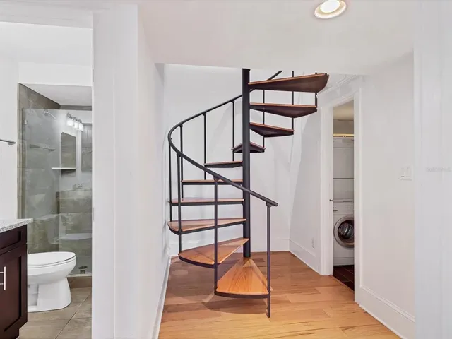 a view of a hallway with wooden floor and a bathroom