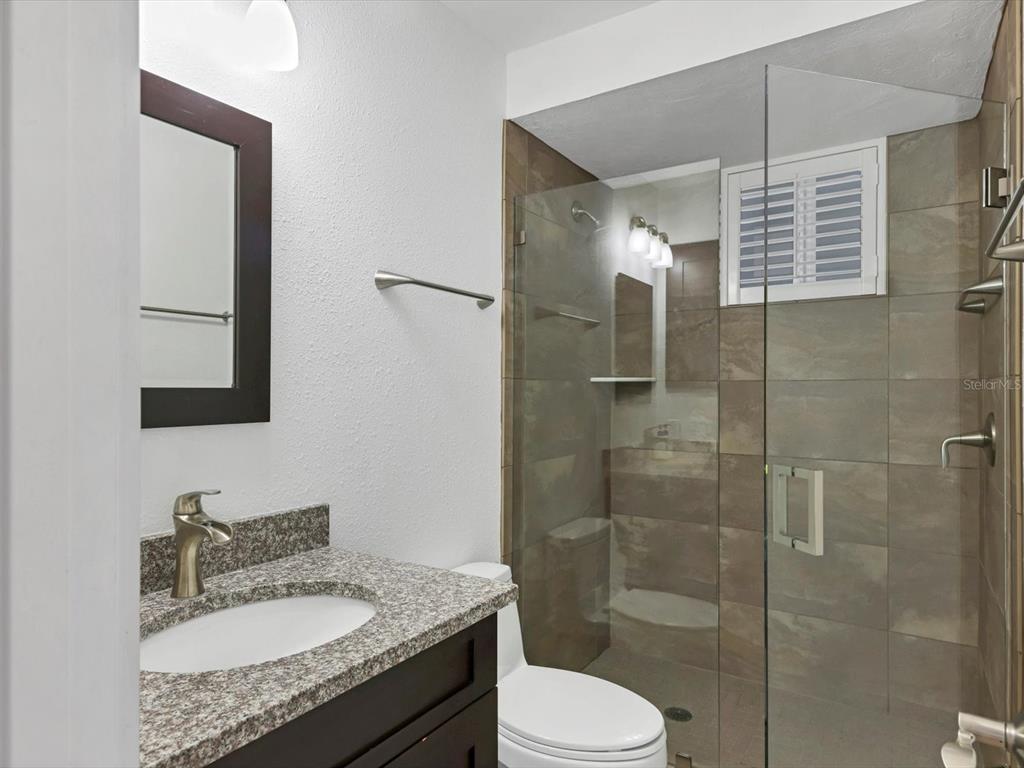 226 Golden Gate Point, Unit 63 Sarasota, FL 34236 - Photo 32 of 48 a bathroom with a granite countertop sink toilet and shower