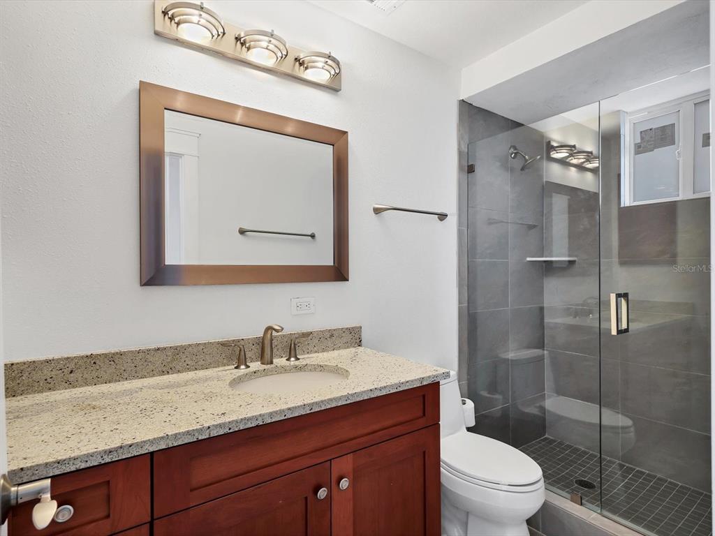 226 Golden Gate Point, Unit 63 Sarasota, FL 34236 - Photo 37 of 48 a bathroom with a granite countertop sink a toilet and a mirror