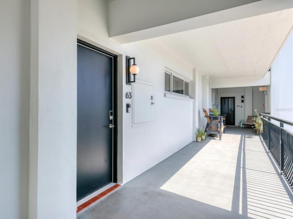 226 Golden Gate Point, Unit 63 Sarasota, FL 34236 - Photo 10 of 48 a hallway with a wooden floor and a large window