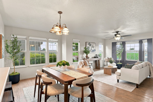 1041 South 1850th Street West Springville, UT 84663 - Photo 10 of 35 Open-concept living area with wood-finish flooring, multiple windows, and a dining area featuring a suspended light fixture