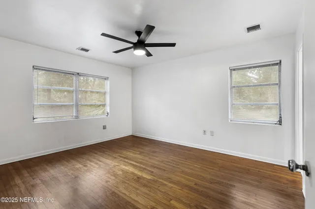 a view of an empty room with a window and wooden floor