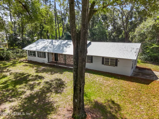 a view of a house with a yard balcony and a large tree