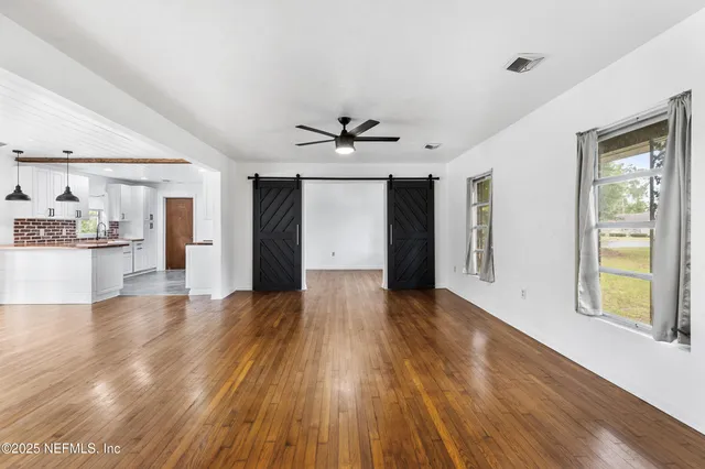 a view of an empty room with window and wooden floor