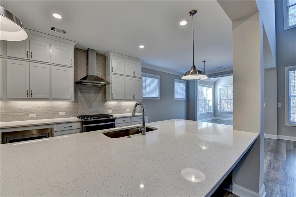3445 Benedict Place Suwanee, GA 30024 - Photo 15 of 59 a kitchen with stainless steel appliances a stove a sink a refrigerator and chairs