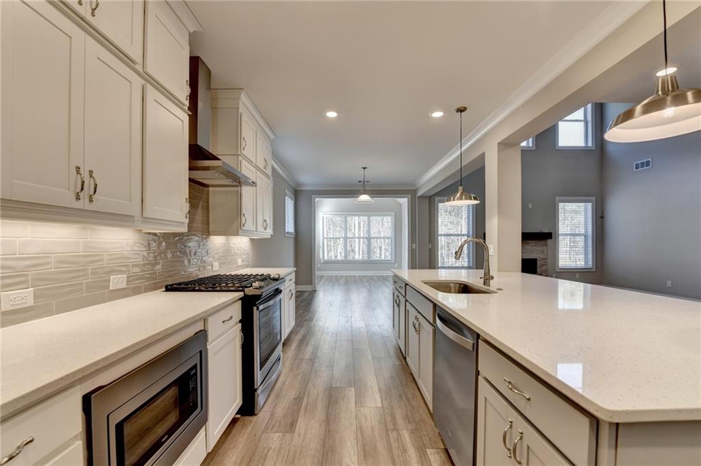 3445 Benedict Place Suwanee, GA 30024 - Photo 9 of 59 a kitchen with stainless steel appliances granite countertop a sink a stove and a wooden floors